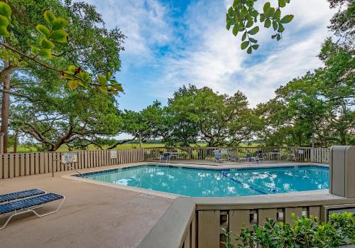una piscina con una valla de madera y árboles en 1228 Creekwatch Villa, en Seabrook Island
