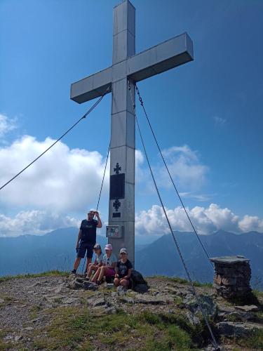 three people sitting in front of a cross on a mountain at Family Home Weißensee in Greifenburg