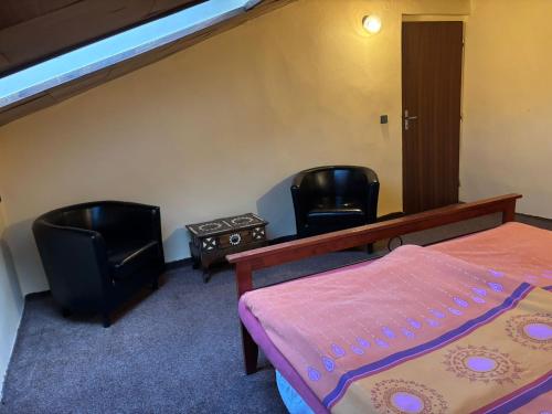 a bedroom with two black chairs and a bed and a staircase at Tatra Roof Room in Nová Lesná
