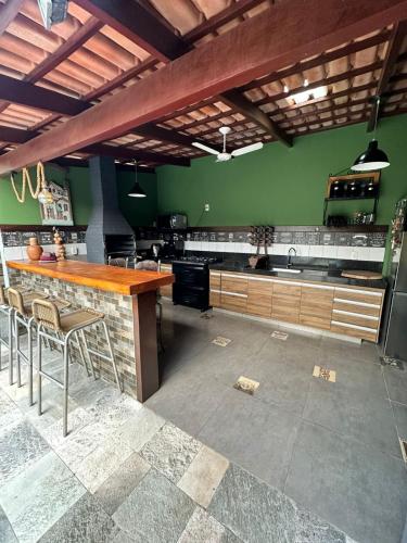 a kitchen with green walls and a bar with stools at Casa do Chico 3 suites in Pirenópolis