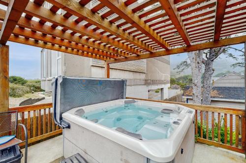 a hot tub on a balcony with a pergola at A Wave From It All in Rockaway Beach