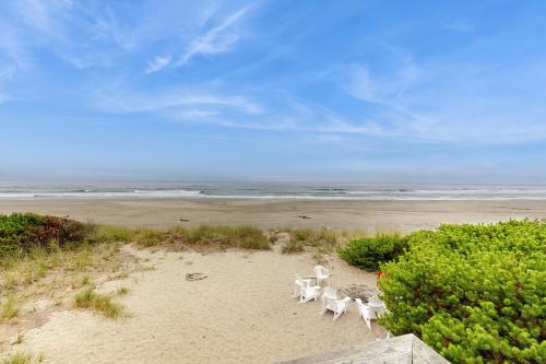 a group of white chairs sitting on a beach at A Wave From It All in Rockaway Beach