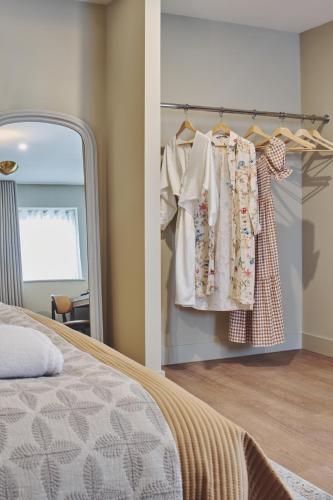 a bedroom with a mirror and a wardrobe with clothes at The Barn Hotel in Meriden