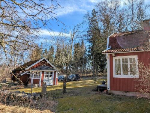 a small red house with a car parked in a parking lot at KAL672-Langasjoe-Trollamala-215 in Långasjö