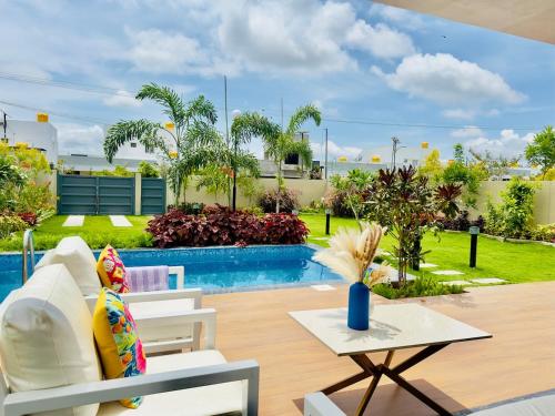 a patio with a table and chairs and a pool at Soul Club - 1hr from HSR, Outdoor Cinema, Pool, Meditation Room, BBQ in Hosūr