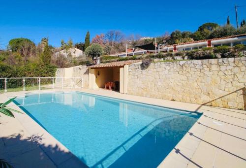 a swimming pool in front of a stone wall at Elegant villa - swimming pool - French Riviera in Montauroux