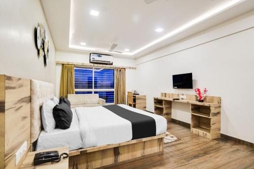 a bedroom with a bed and a desk and a television at Super Townhouse Oak PTC Indore Junction in Indore