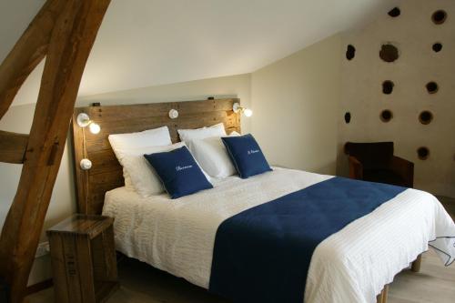a bedroom with a large bed with blue and white pillows at Le Colombier - Chambre Mésange in Baule
