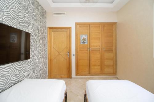 a bedroom with two beds and a closet at Luxe & sérénité près de l Aireport Mohamed 5, votre Havre de Paix in Nouaseur