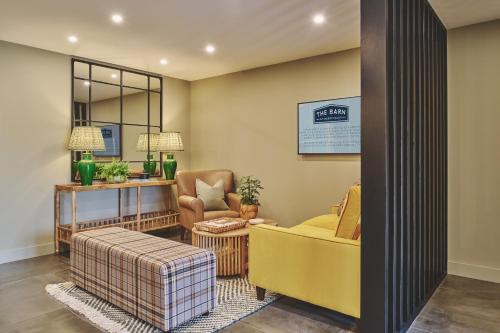 a living room with a yellow couch and a chair at The Barn Hotel in Meriden