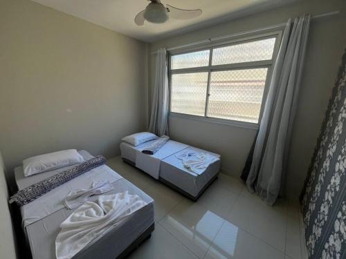 two beds in a room with a window at Itapuã - 4 Minutos da Praia - Apartamento Espaçoso - 3 Quartos in Vila Velha