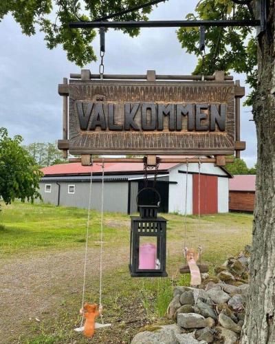 a sign that reads valley korman hanging from a tree at BLE596-Soelvesborg-Aeskemovaegen-26 in Sandbäck