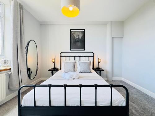 a bedroom with a bed with white sheets and a yellow light at Skyline View Apartment in Edinburgh