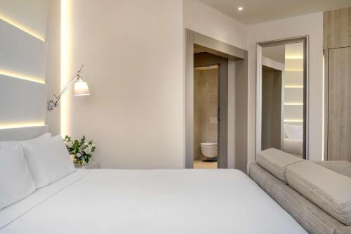 a bedroom with a large white bed and a couch at NH Málaga in Málaga