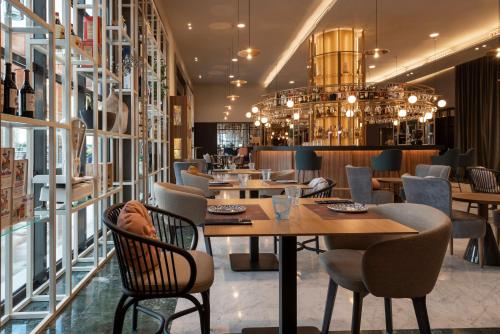 a restaurant with tables and chairs and a chandelier at NH Málaga in Málaga