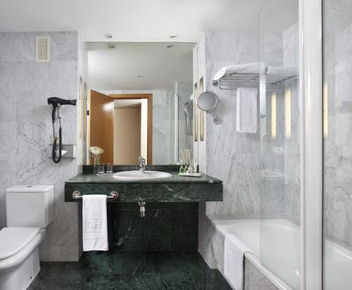 a bathroom with a sink and a tub and a toilet at NH Málaga in Málaga