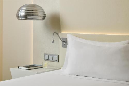 a bed with a white pillow and a lamp at NH Málaga in Málaga