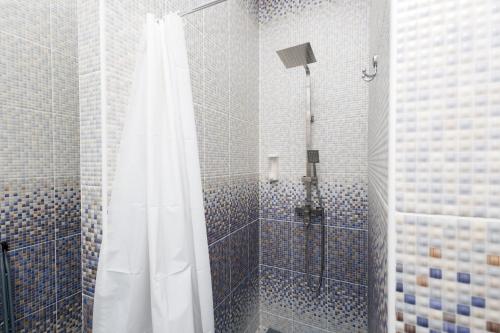 a shower with a white shower curtain in a bathroom at Aparthotel Royal Status in Chişinău