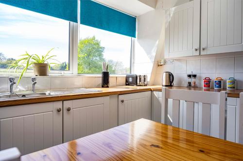 a kitchen with white cabinets and a sink and a window at Spacious apartment sleeps 6 - Uni, sports, trades in Nottingham