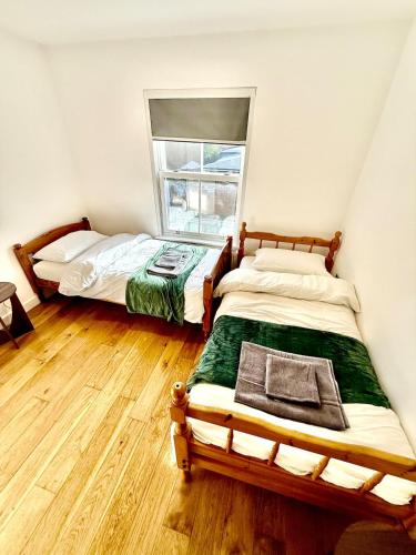 two beds in a room with a window at Beautiful Modern 2 Bed house combined with a vintage feel near Central Cambridge Sleeps 4 in Cambridge
