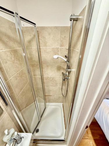a shower with a glass door next to a sink at Beautiful Modern 2 Bed house combined with a vintage feel near Central Cambridge Sleeps 4 in Cambridge