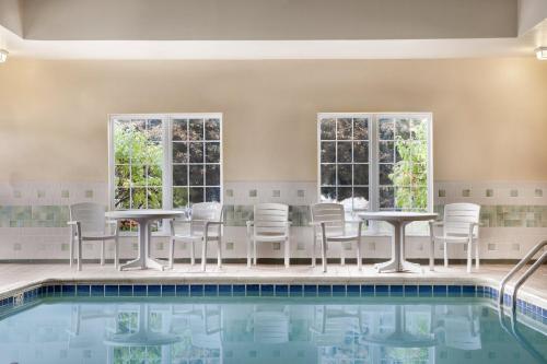 - une piscine avec des chaises, des tables et des fenêtres dans l'établissement Country Inn & Suites by Radisson, Kalamazoo, MI, à Kalamazoo