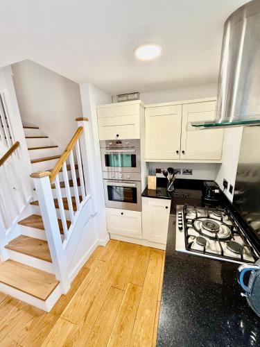 a kitchen with white cabinets and a staircase at Beautiful Modern 2 Bed house combined with a vintage feel near Central Cambridge Sleeps 4 in Cambridge