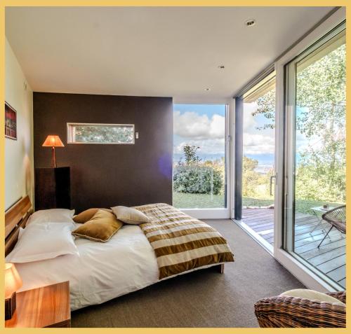 una camera da letto con un letto grande e una grande finestra di Villa vue Lac Léman et montagne Proche Genève a Cranves-Sales
