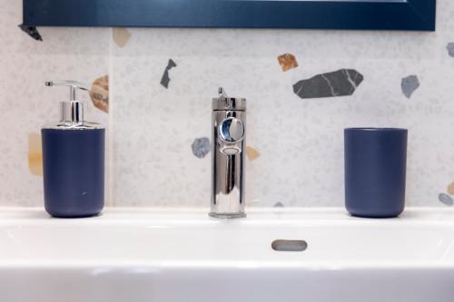 a sink with two toothbrushes and two cups on it at Topa Casa Gîte d'hôtes à Creil in Creil