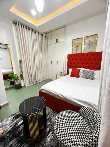 a bedroom with a bed with a red headboard and chairs at Service Apartment in Abuja