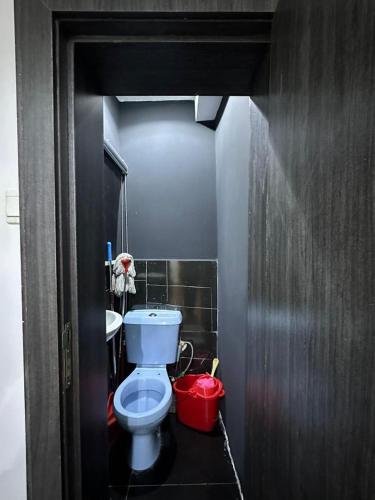 a bathroom with a toilet and a red bucket at Service Apartment in Abuja