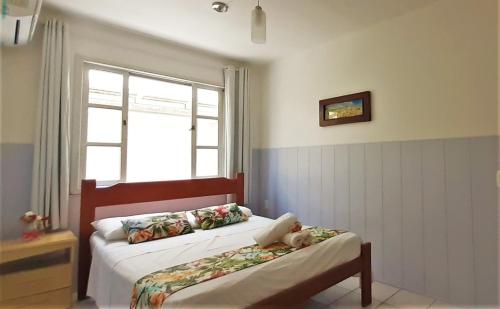 two beds in a room with a window at Mares e Flores de Bombinhas in Bombinhas