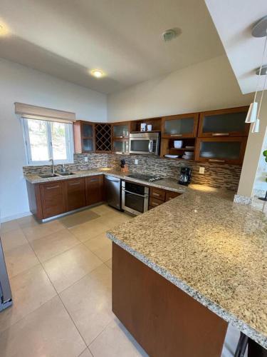 a large kitchen with granite counter tops and a stove at Oceanview Punta Arrocito Luxury Condo, Near Arrocito Beach in Santa Maria Huatulco