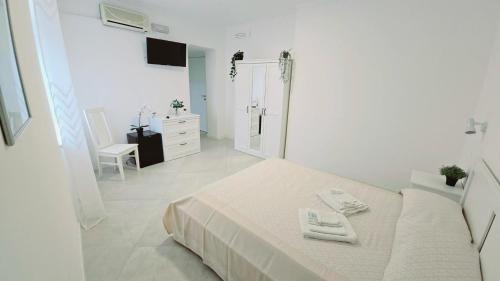 a white bedroom with a bed and a bathroom at Hotel paradiso in Scalea