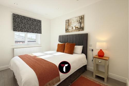 オールダーショットにある3 bedroom House Contractors and Groups sleeps 5のオレンジ色の枕が付いた大きなベッドのある寝室