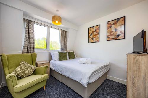 a bedroom with a bed and a chair and a tv at Spacious apartment sleeps 6 - Uni, sports, trades in Nottingham