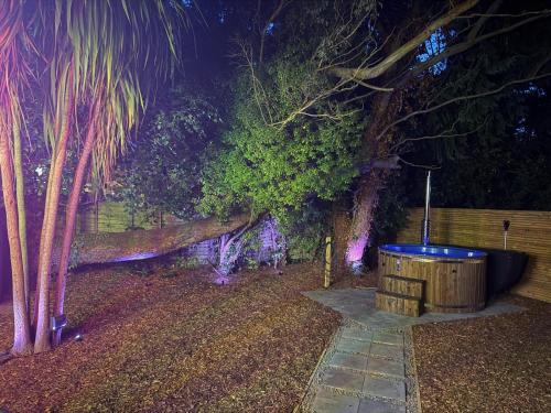 drewniana beczka stojąca nocą obok drzewa w obiekcie The Funky Hideaway with Hot Tub w mieście Bangor