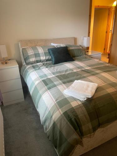 a bedroom with a large bed with a plaid blanket at 33 Liberator Drive, Kirkwall in Orkney