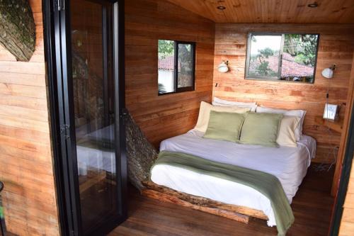 Una cama pequeña en una habitación con paredes de madera. en Treehouse, en Santa Helena