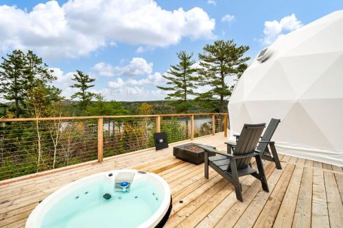 a bath tub sitting on a deck with a chair at Nalu Retreat Glamping Domes in Porters Lake