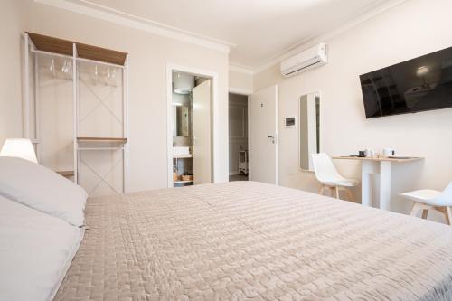 a white bedroom with a large bed and a kitchen at ELEGANCE Calasetta's Rooms in Calasetta