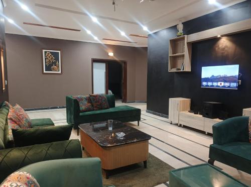 a waiting room with green chairs and a flat screen tv at Destination Home in Islamabad