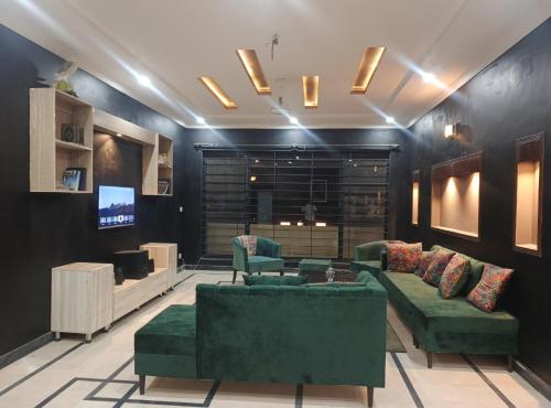 a living room with green couches and a tv at Destination Home in Islamabad