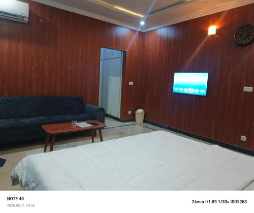 a bedroom with a bed and a couch and a tv at Destination Home in Islamabad