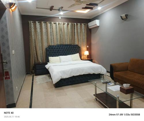 a bedroom with a bed and a couch and a table at Destination Home in Islamabad