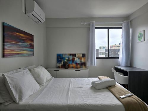 a bedroom with a bed and a desk and a window at Apê à 5min da Praia com Piscina na Coberftura in Maceió