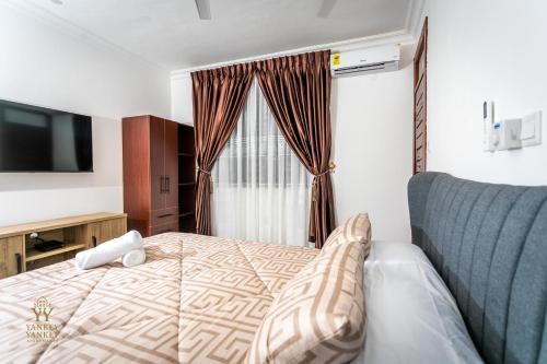 a hotel room with a bed and a television at Yankey Yankey Apartments-Kansaworado in Takoradi