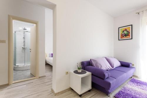 a living room with a purple couch and a bathroom at Studio Goga in Trogir