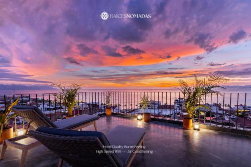 a sunset on the roof of a building with chairs at Raices Nomadas Boutique Hotel Vallarta in Puerto Vallarta