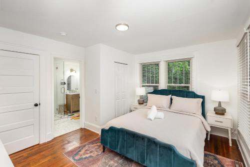 a white bedroom with a large bed with a blue headboard at Walkable City Trendy Hideout for Foodies - 3BR-2BA in Charlotte